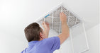 man changing air filter in ceiling